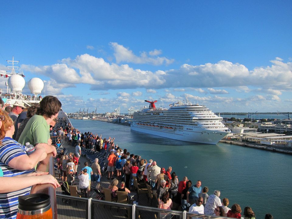 View from the top of a Carnival cruise ship filled with people while docked in Miami, Florida