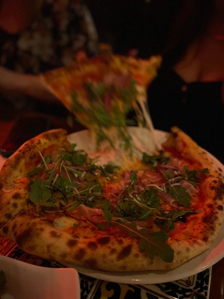 Person pulling a slice of wood-oven pizza at Gigi's in St. Catharines