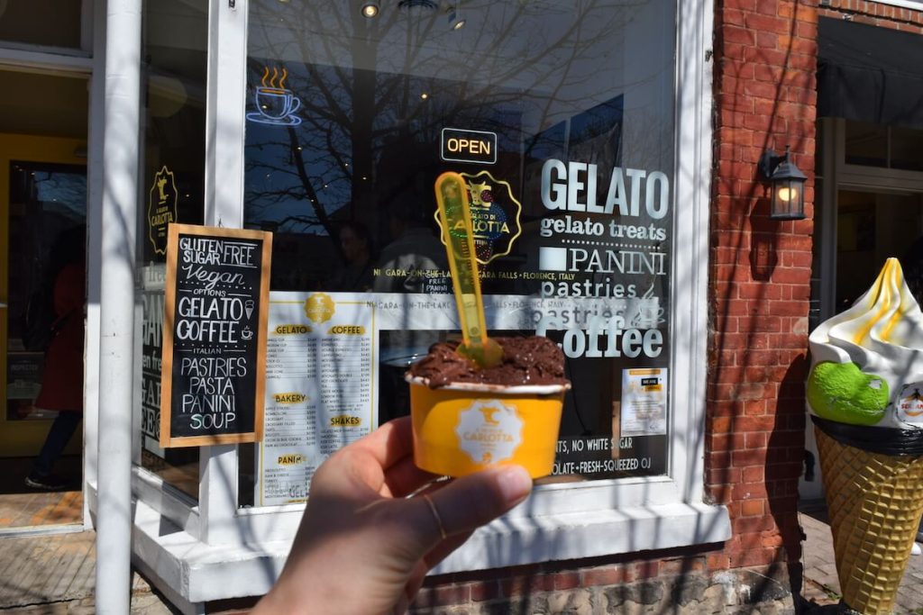 Personal holding cup of gelato in front of Il Gelato di Carlotta on Queen Street in Niagara on the Lake