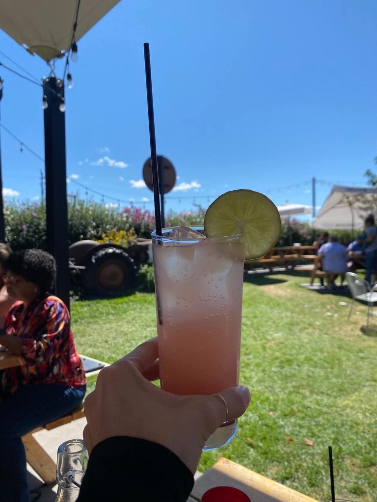 Person holding a cocktail with the BarrelHead patio in the background at Pillitteri Winery in Niagara-on-the-Lake