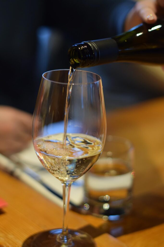 Person pouring white wine into a wine glass