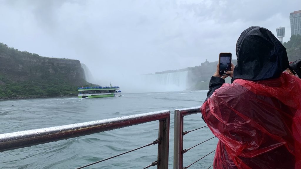Person taking photos of the falls and Maid of the Mist from the Niagara City Cruises boat tour
