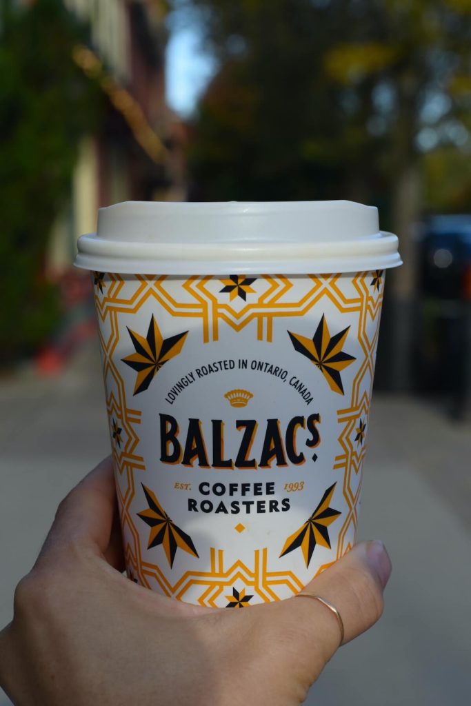 Person holding a coffee cup from Balzac's standing on Queen Street in Niagara-on-the-Lake